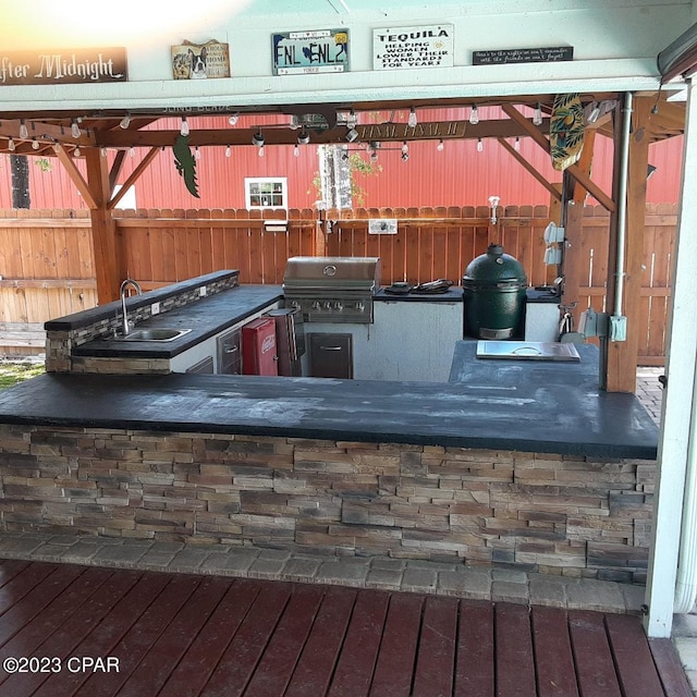 view of terrace featuring an outdoor kitchen, a grill, sink, and a wooden deck