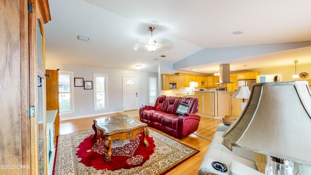 living room featuring ceiling fan, vaulted ceiling, and light hardwood / wood-style flooring