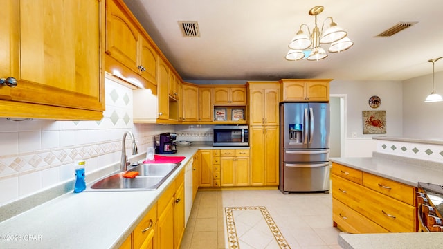 kitchen featuring sink, backsplash, stainless steel appliances, decorative light fixtures, and a notable chandelier