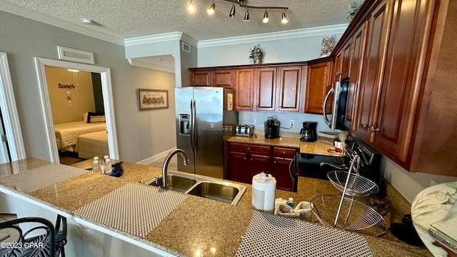 kitchen with a kitchen bar, stainless steel appliances, a textured ceiling, and track lighting