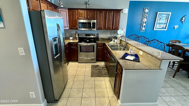 kitchen with kitchen peninsula, sink, stainless steel appliances, light tile flooring, and light stone countertops