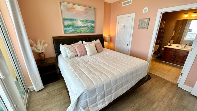 bedroom with dark hardwood / wood-style floors, ensuite bathroom, and sink