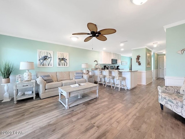 living room with light wood-type flooring, ceiling fan, and crown molding