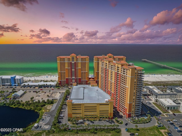 aerial view at dusk with a water view and a beach view