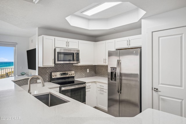 kitchen featuring sink, stainless steel appliances, white cabinets, light stone counters, and tasteful backsplash