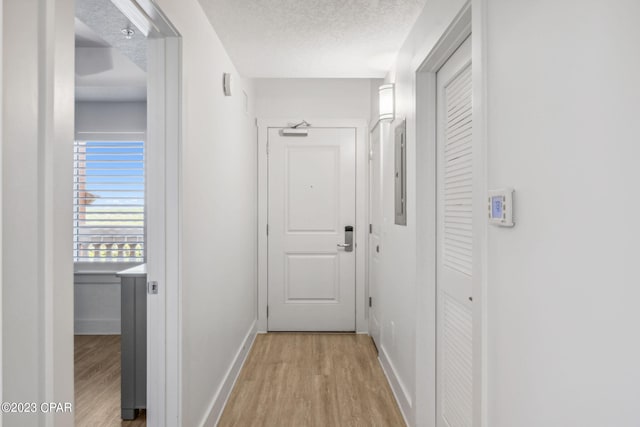 corridor with a textured ceiling and light wood-type flooring