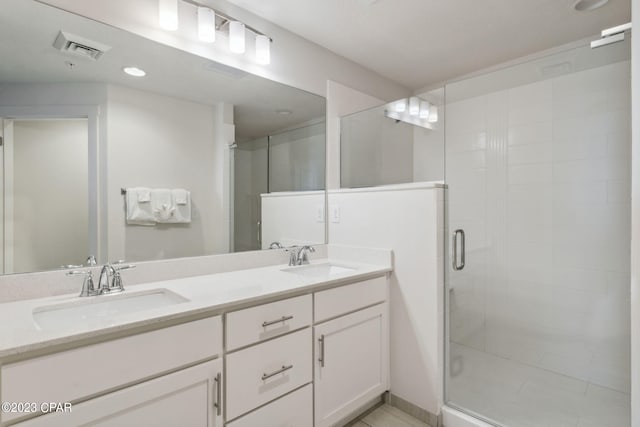 bathroom with oversized vanity, a shower with shower door, and dual sinks