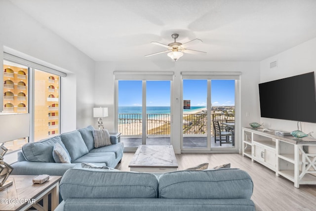 living room with ceiling fan, light wood-type flooring, and a water view