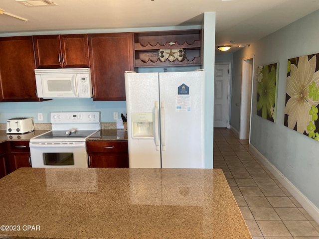 kitchen featuring light tile patterned flooring, light stone countertops, and white appliances