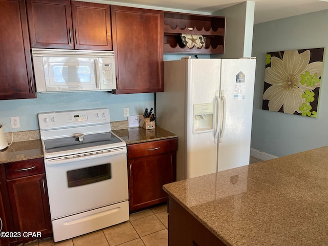 kitchen with dark stone counters, white appliances, and light tile patterned floors