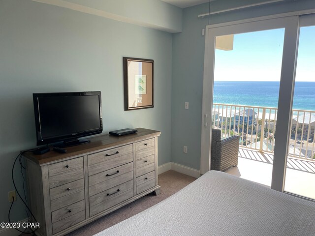 carpeted bedroom featuring a water view, a beach view, and access to exterior