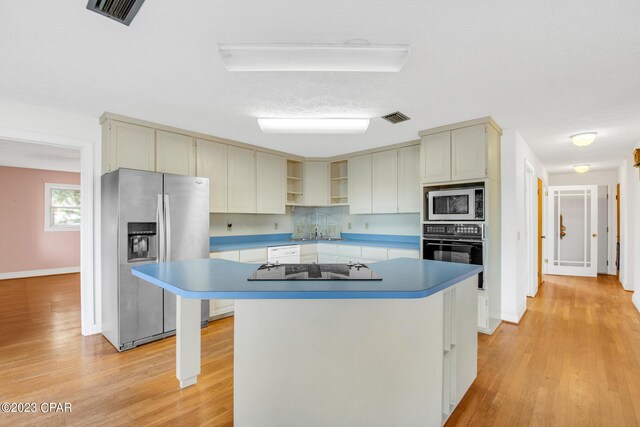 kitchen with sink, light wood-type flooring, a kitchen island, and black appliances