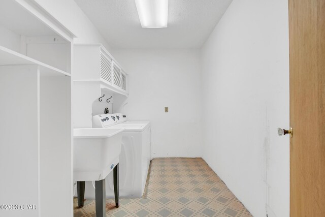 laundry area with sink, independent washer and dryer, and a textured ceiling