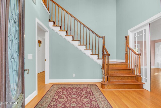 staircase featuring a towering ceiling and wood-type flooring