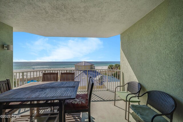 balcony with a water view and a view of the beach