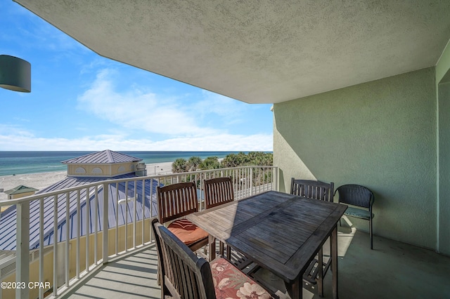 balcony featuring a view of the beach and a water view