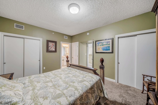 carpeted bedroom with a textured ceiling, ensuite bath, and multiple closets