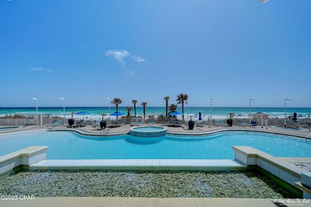 view of pool featuring a water view, a community hot tub, and a patio