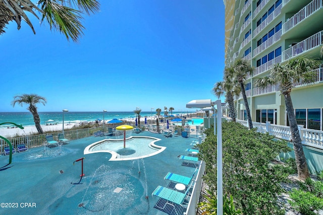 exterior space featuring a water view, a beach view, and a swimming pool