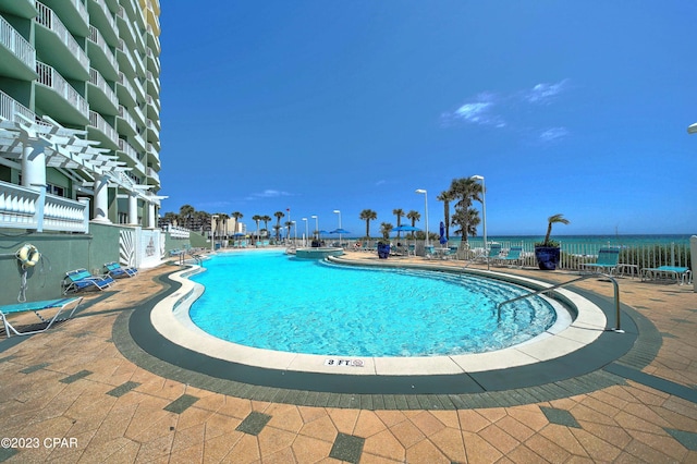 view of pool featuring a patio and a water view