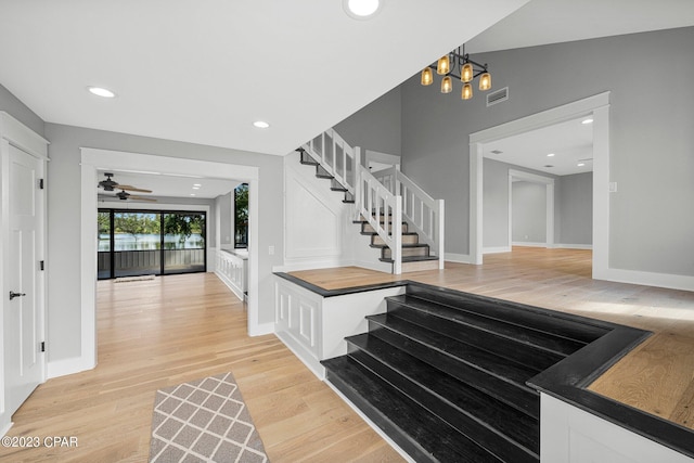 entrance foyer with ceiling fan with notable chandelier and light wood-type flooring