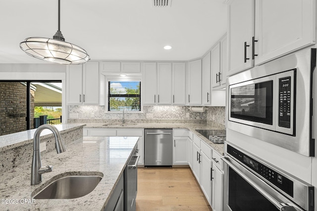 kitchen with white cabinets, appliances with stainless steel finishes, pendant lighting, and sink