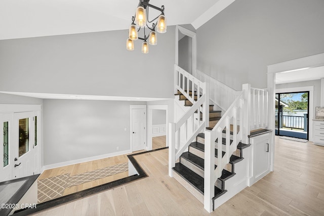 staircase with hardwood / wood-style floors, high vaulted ceiling, a chandelier, and french doors