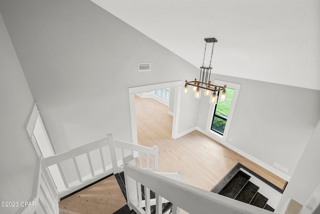 stairs featuring hardwood / wood-style floors, high vaulted ceiling, and a chandelier