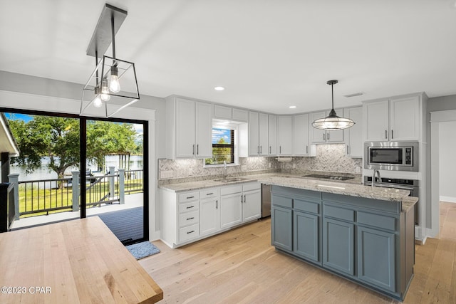 kitchen with decorative light fixtures, a center island, sink, and appliances with stainless steel finishes