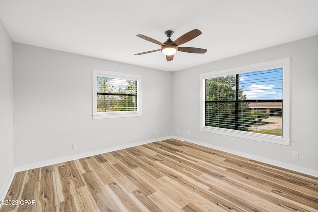 empty room with ceiling fan, a wealth of natural light, and light hardwood / wood-style flooring