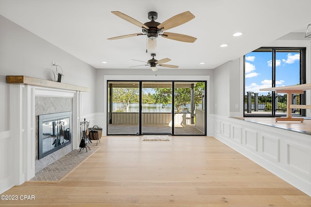 unfurnished living room with a tile fireplace, light hardwood / wood-style flooring, and ceiling fan