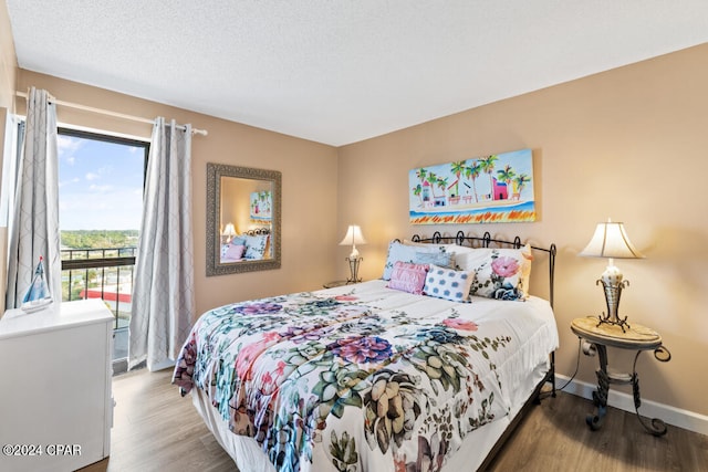 bedroom with a textured ceiling, baseboards, and wood finished floors