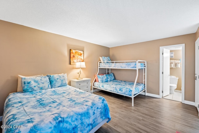 bedroom featuring ensuite bath, wood finished floors, and baseboards