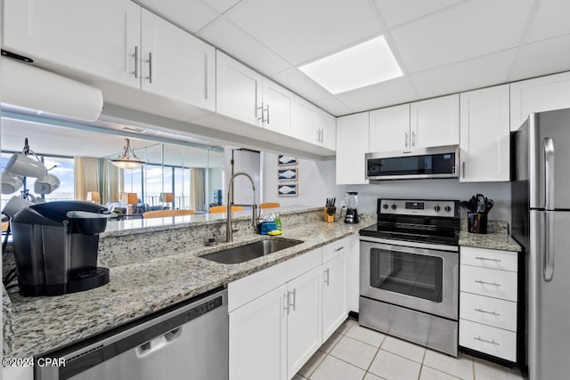 kitchen with stainless steel appliances, a drop ceiling, a sink, and white cabinetry