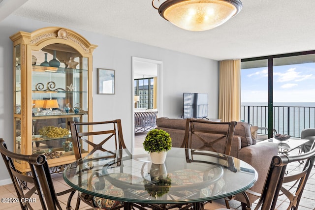 dining area featuring floor to ceiling windows, a textured ceiling, and light tile patterned flooring