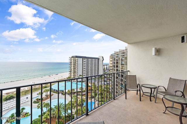 balcony with a water view and a view of the beach