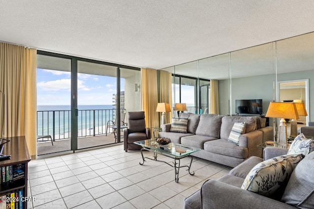 tiled living area with expansive windows, a textured ceiling, and a water view