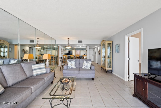 living room with visible vents, a textured ceiling, baseboards, and light tile patterned floors