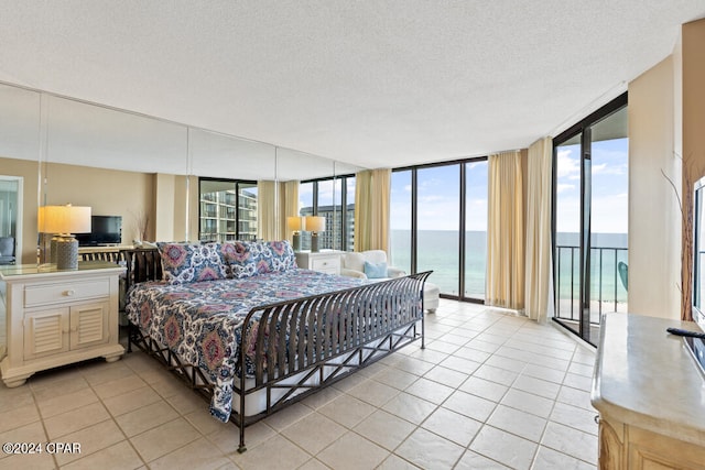 bedroom with expansive windows, light tile patterned floors, a textured ceiling, and access to exterior