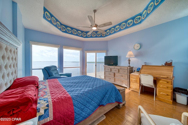 bedroom with ceiling fan, a textured ceiling, and hardwood / wood-style flooring