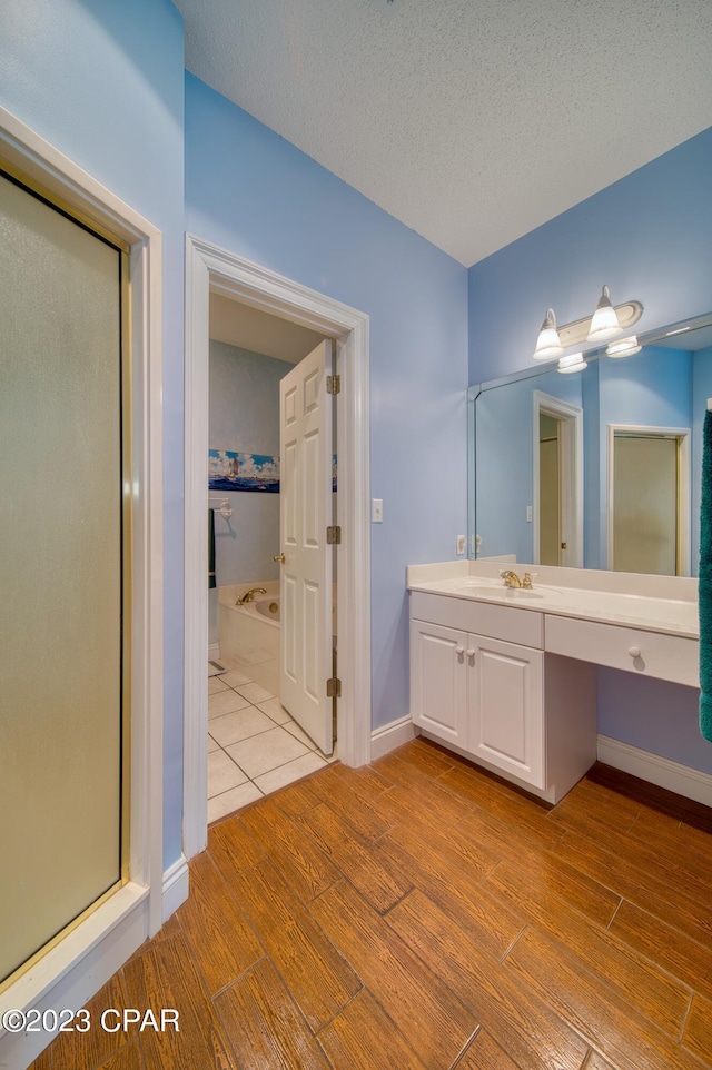 bathroom featuring vanity, a textured ceiling, hardwood / wood-style flooring, and separate shower and tub