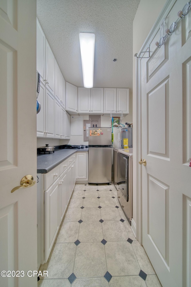 kitchen featuring white cabinetry, stainless steel fridge, and a textured ceiling