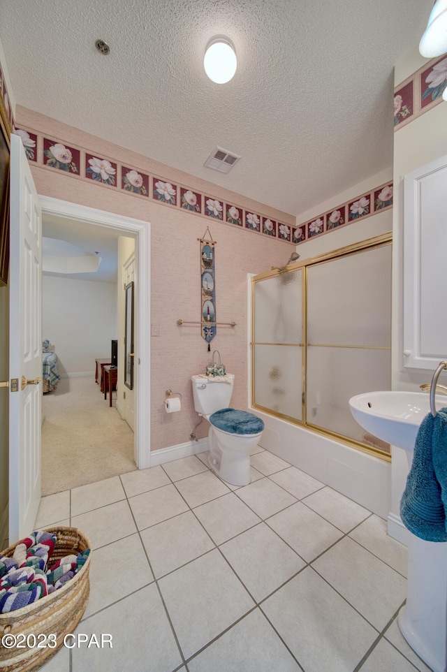 bathroom with shower / bath combination with glass door, tile patterned floors, a textured ceiling, and toilet