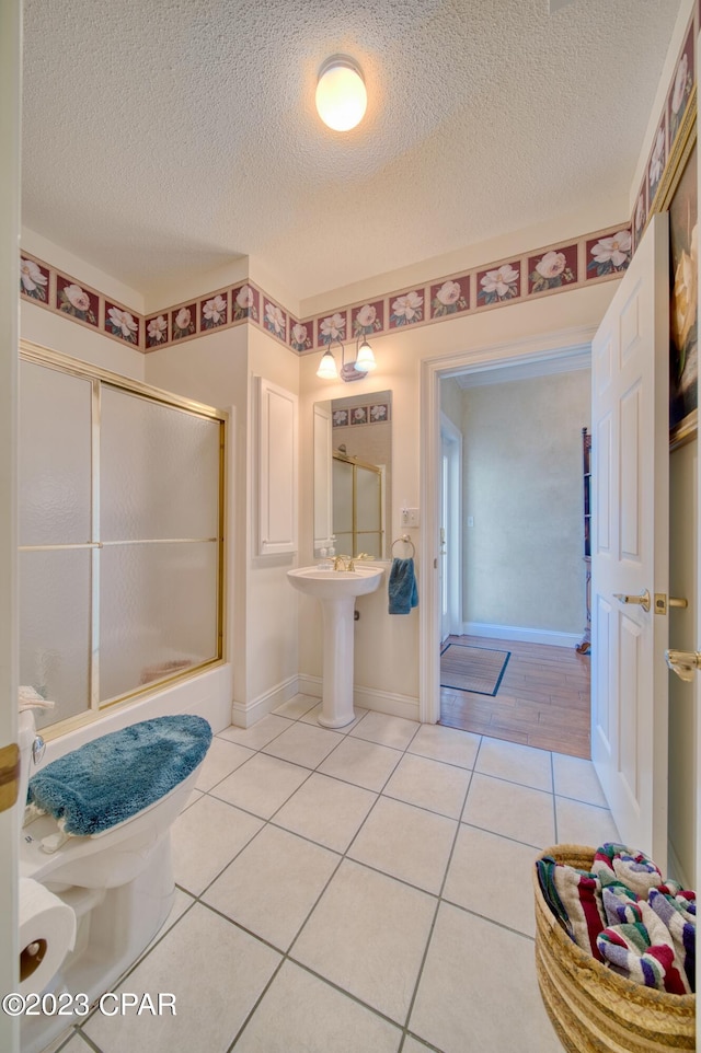 bathroom with tile patterned flooring, a textured ceiling, and toilet