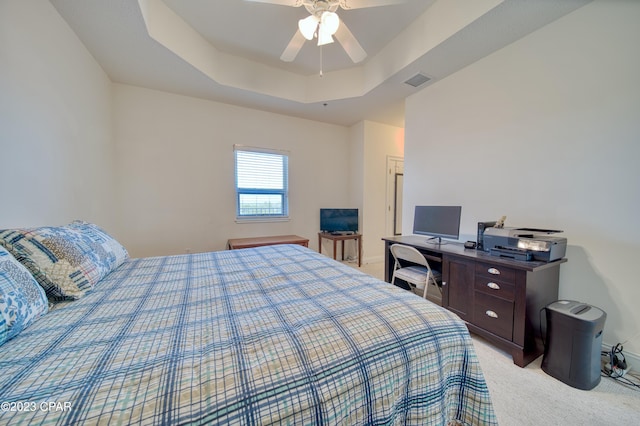 bedroom with light carpet, a tray ceiling, and ceiling fan