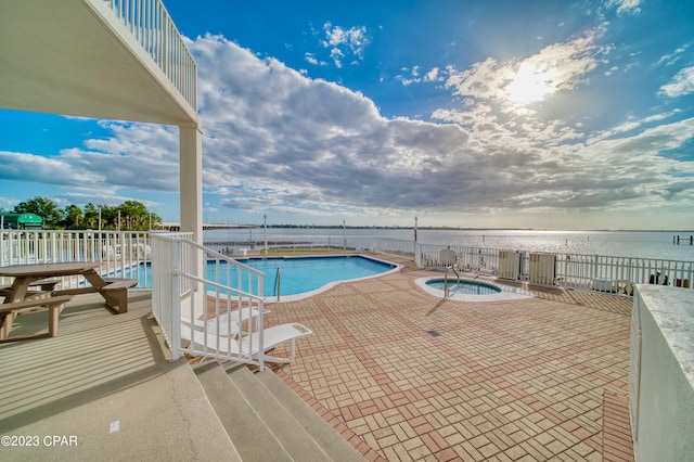 view of pool featuring a patio area, a water view, and a community hot tub