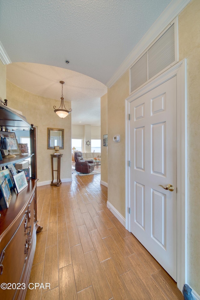 corridor featuring a textured ceiling and light hardwood / wood-style floors