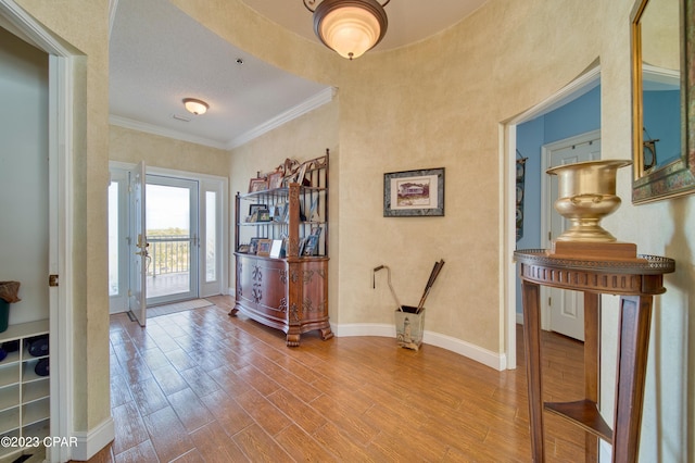 foyer with wood-type flooring, a textured ceiling, and ornamental molding