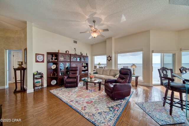 living room featuring a healthy amount of sunlight, ceiling fan, wood-type flooring, and a textured ceiling