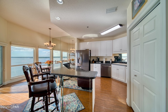 kitchen featuring a textured ceiling, a water view, white cabinetry, and stainless steel appliances